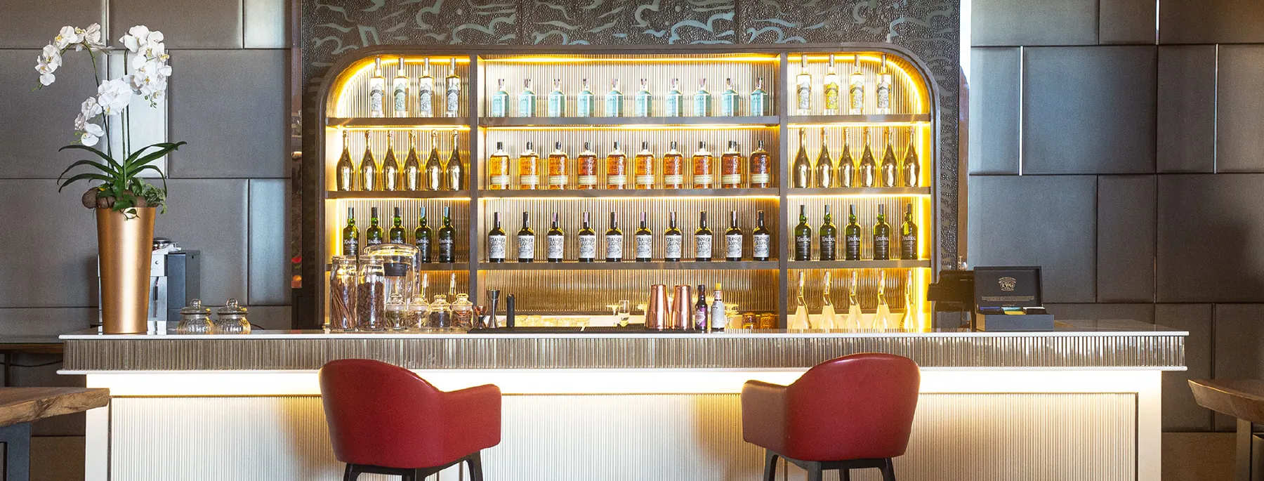 Milano Bar: arched, backlit bottle wall above the stone counter