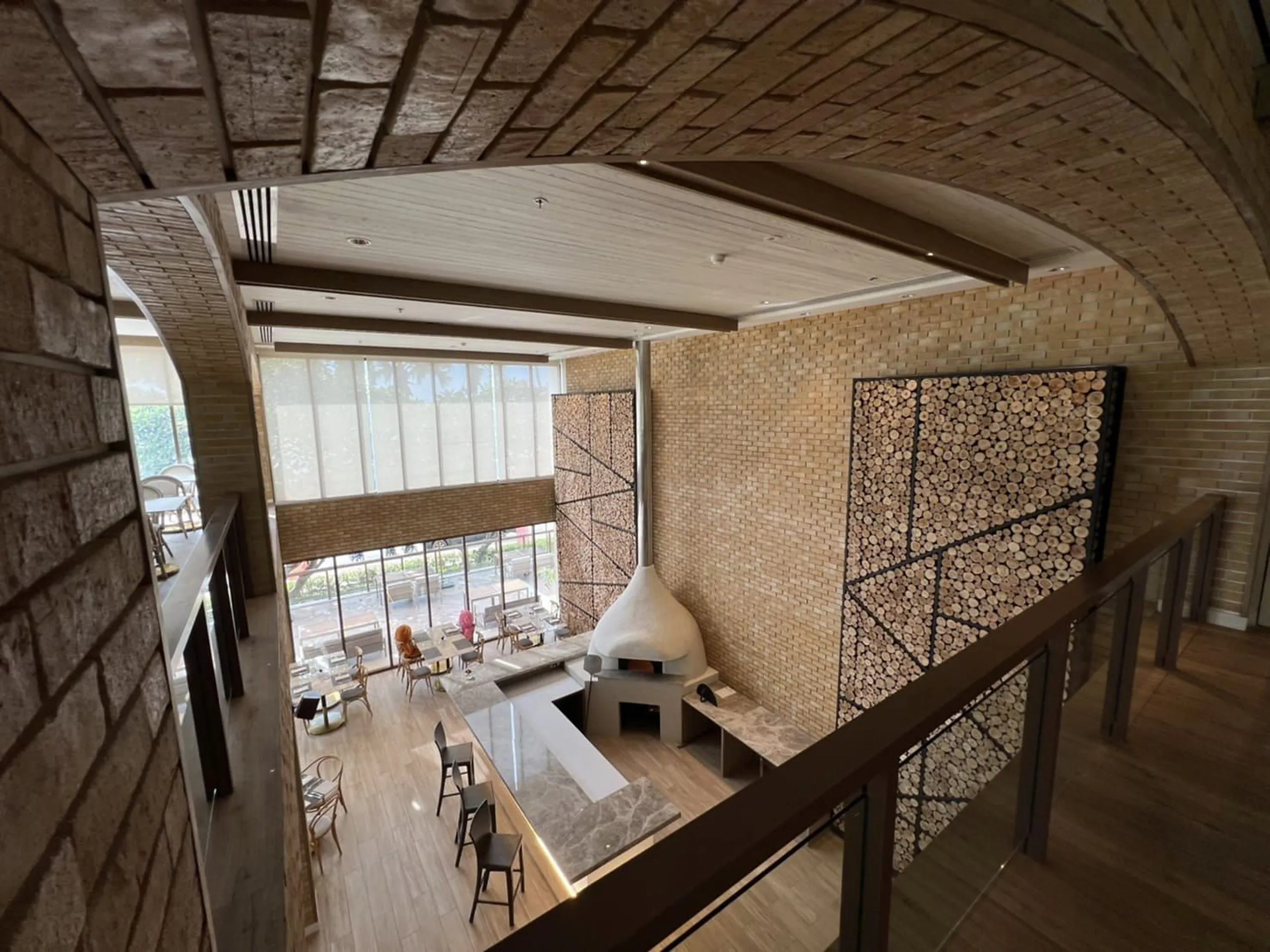 Prego: the dining room, the wood-fired oven and the log wall rising beside the mezzanine